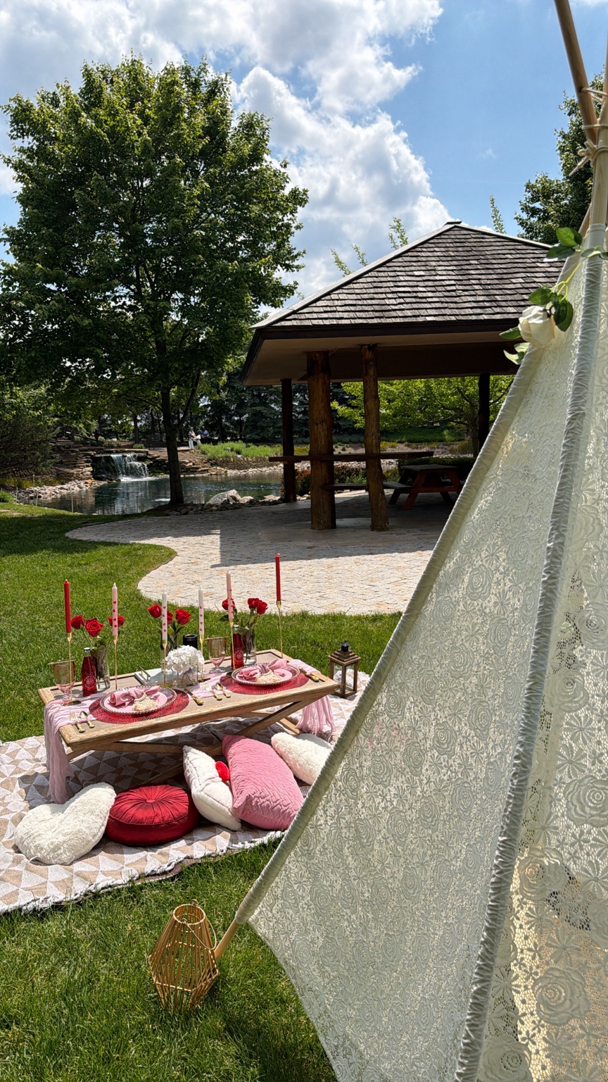 Outdoor picnic setting with cushions and a low table beside a canvas tent