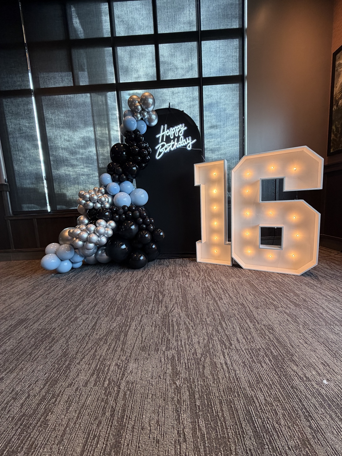 Black and silver balloon backdrop with illuminated sixteen marquee numbers