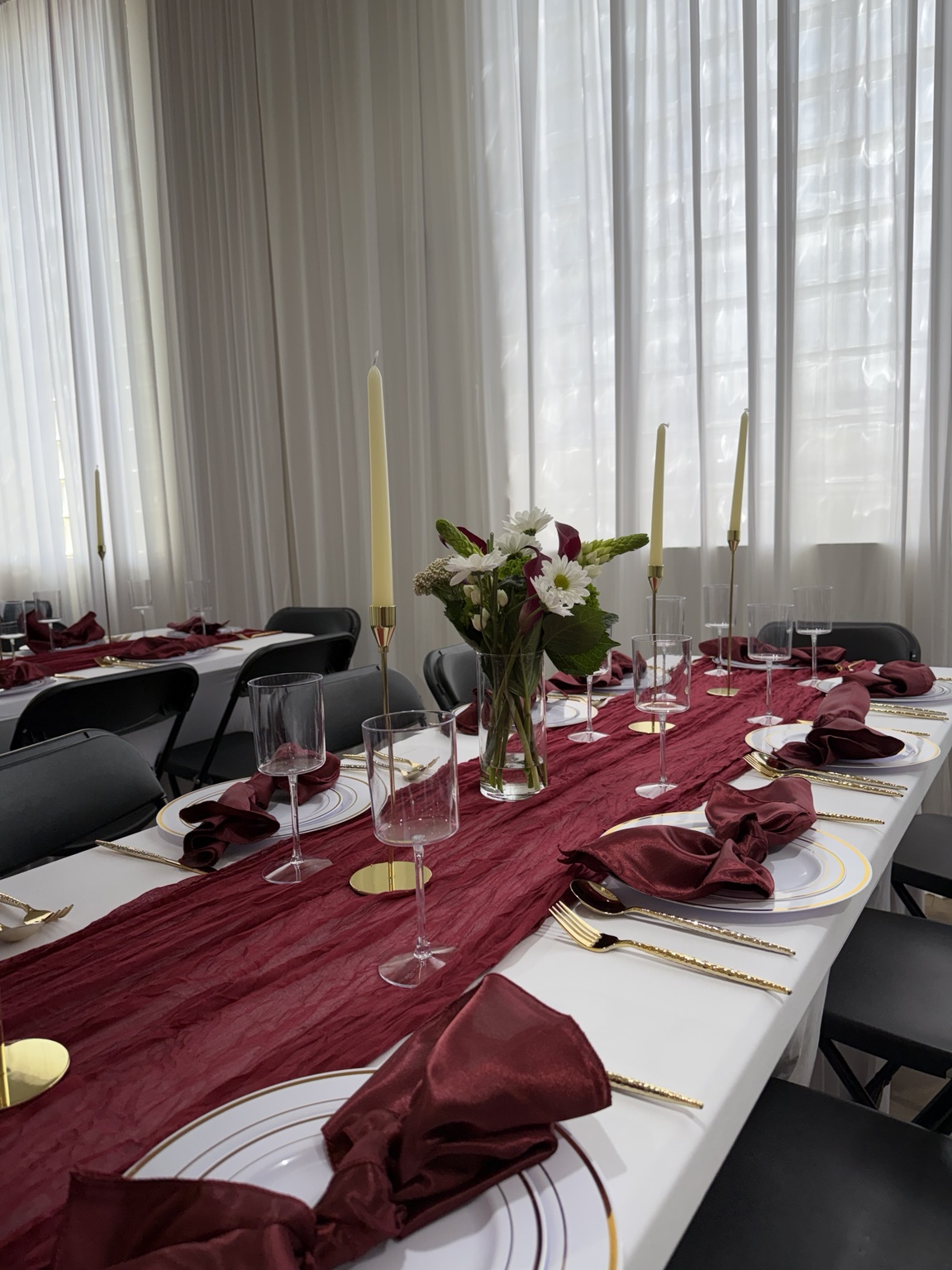 Burgundy table runner, floral centerpiece, gold table details, and candles