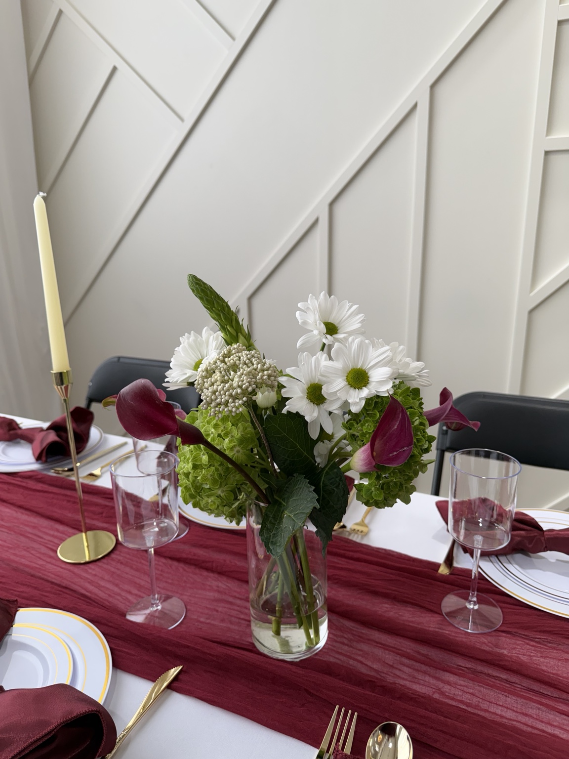 White and burgundy floral centerpiece on a wine-colored runner