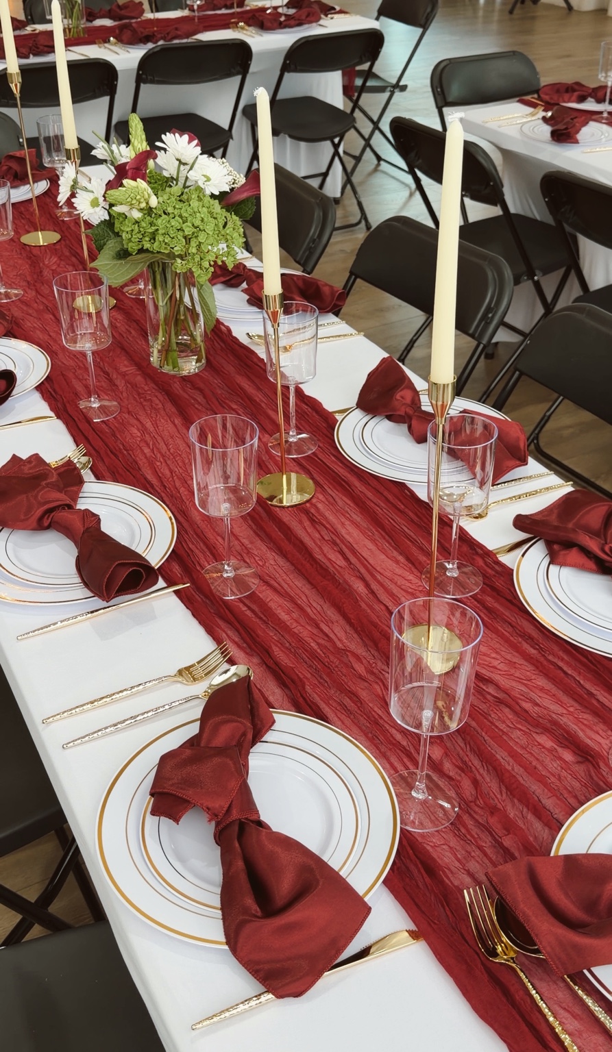 Burgundy table setting with gold taper candles and floral centerpiece
