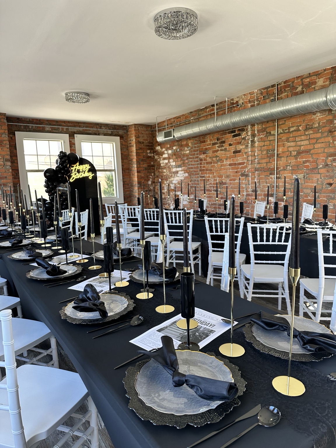 Black and gold tablescape with taper candles and white chairs